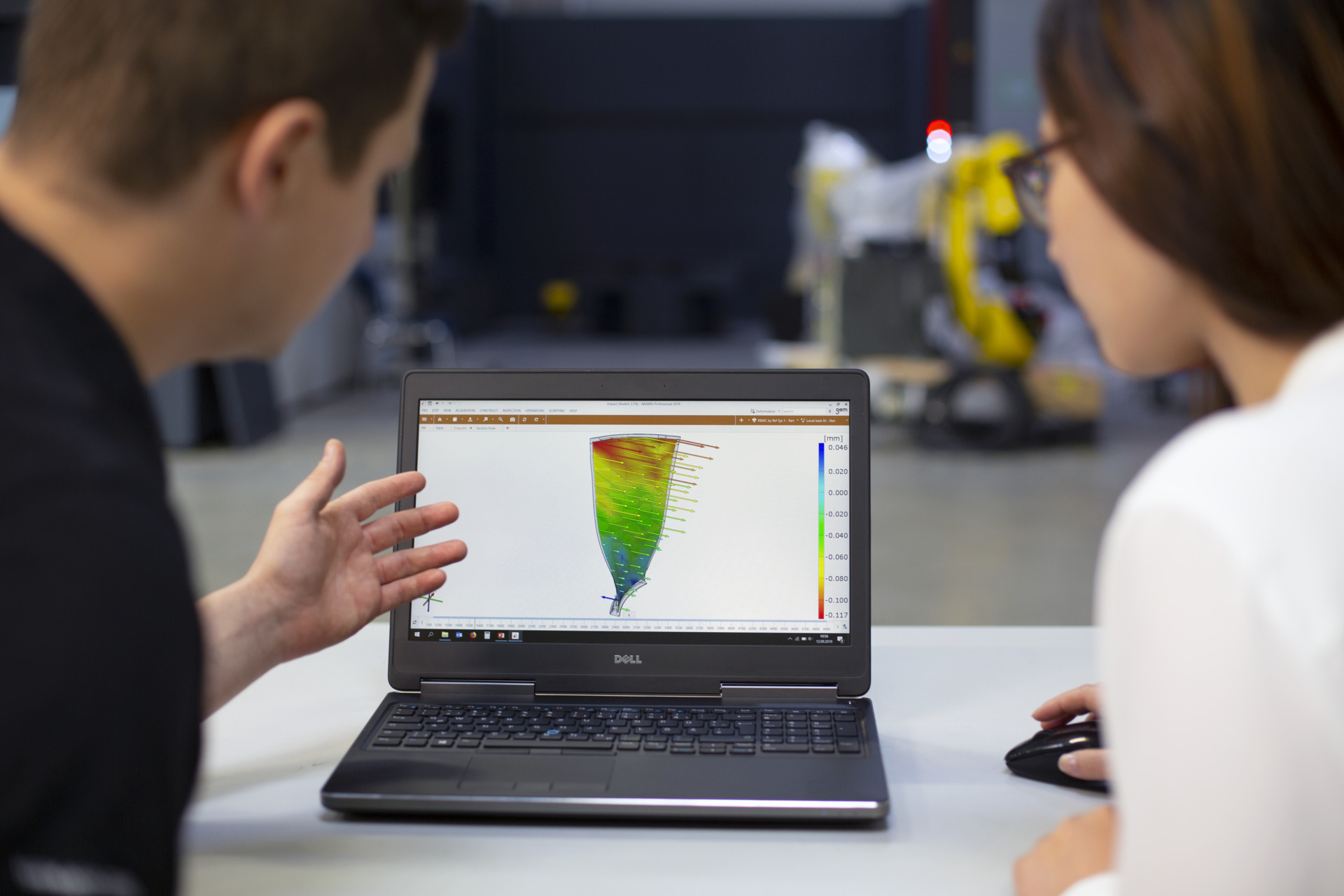 Two analysts look at the results of vibration analysis on a laptop.